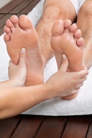 Close up of female masseuse giving foot massage to male s bare footの写真素材