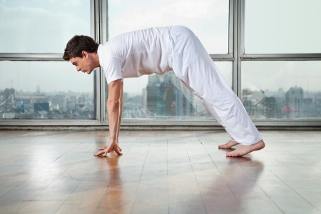 Side view of a young man practicing yoga called Downward Facing Dog at gymの写真素材