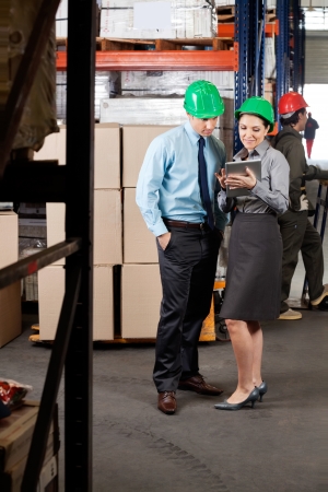 Young female supervisor and colleague using digital tablet at warehouseの写真素材