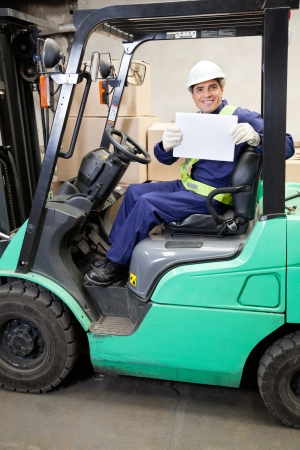 Portrait of forklift driver displaying blank placardの写真素材
