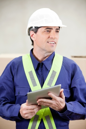 Warehouse worker with digital tablet standing in warehouseの写真素材