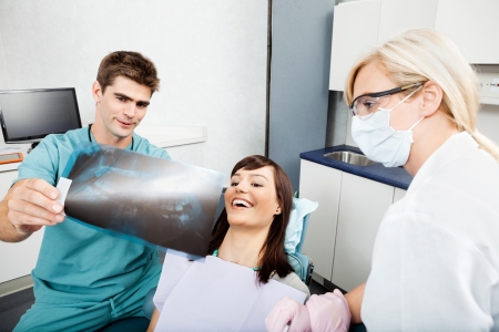 Dentist With Female Assistant Showing X-Ray Image To Patientの写真素材