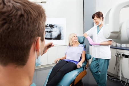 Dentist Examining X-Ray Image With Female Assistant Communicatinの写真素材