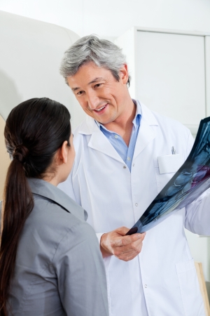 Radiologist Looking At Patient While Holding X-rayの写真素材