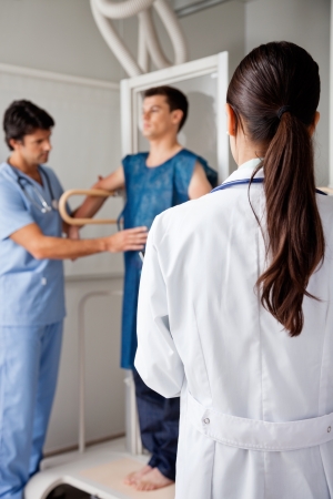 Doctor With Technician Assisting Patient For X-rayの写真素材