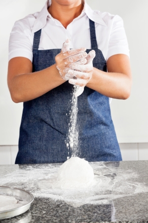 Female Chef Adding Flour To Doughの写真素材