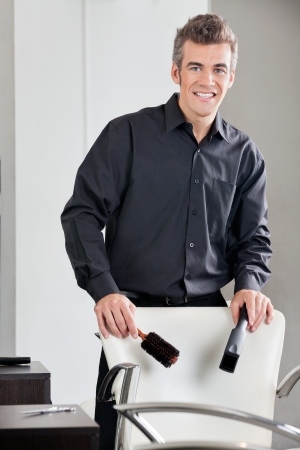 Happy Hairdresser Holding Straightener And Brushの写真素材