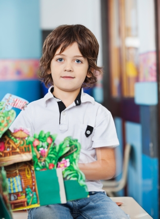 Boy With Popup Book Sitting On Desk In Classroomの写真素材