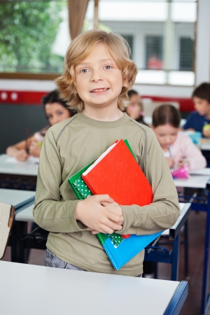 Schoolboy With Books Standing At Deskの写真素材