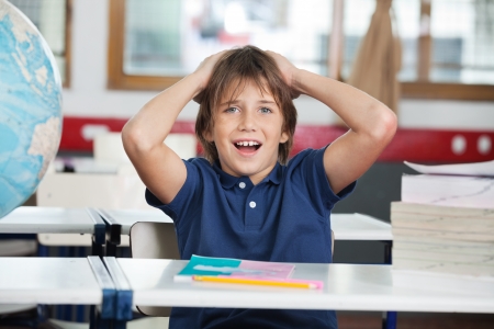 Shocked Little Boy With Globe And Books At Deskの写真素材