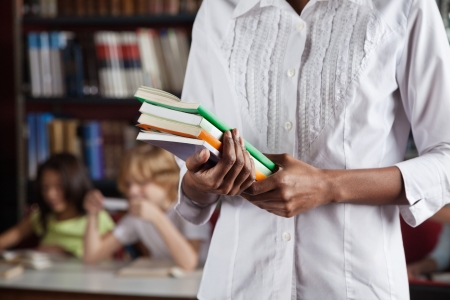 Librarian Holding Books While Standing In Library