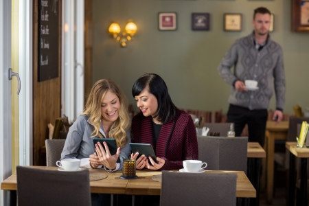 Female Friends Using Digital Tablets At Cafeの写真素材