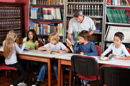 Teacher Showing Book To Schoolboy In Libraryの写真素材