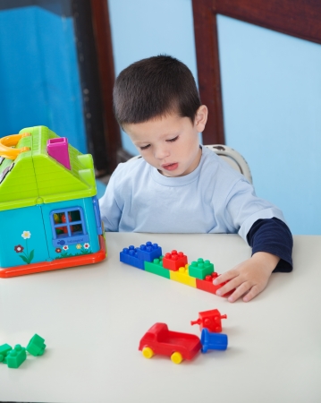Boy Playing With Toys At Desk In Preschoolの写真素材