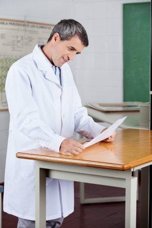 Male Teacher Reading Paper At Deskの写真素材