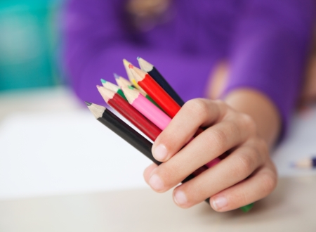 Girl Holding Colored Pencils At Deskの写真素材