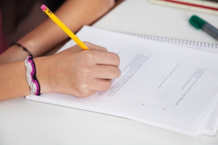 Schoolgirl Writing On Paper At Desk