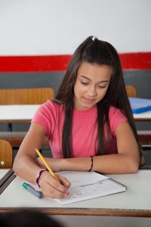 High School Student Writing In Book At Deskの写真素材
