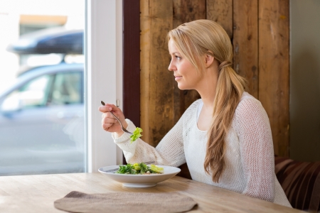 Woman Looking Through Window While Eating Saladの写真素材