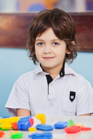 Portrait of cute boy with blocks on desk at kindergartenの写真素材