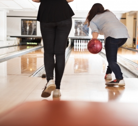 Rear view of young women playing in bowling alley