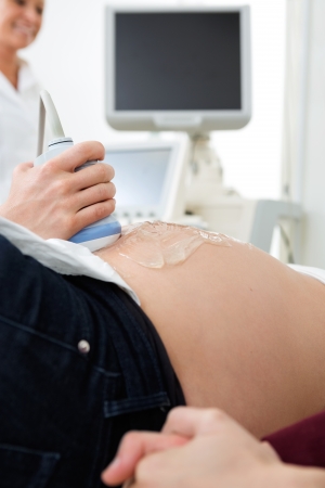 Midsection closeup of pregnant woman going through an ultrasound scan in clinicの写真素材