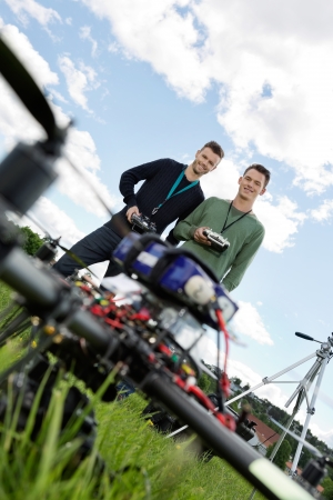 Low angle view of young technicians standing with remote controls of UAV in park