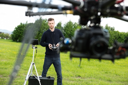 Young male engineer flying  UAV helicopter with remote control in park