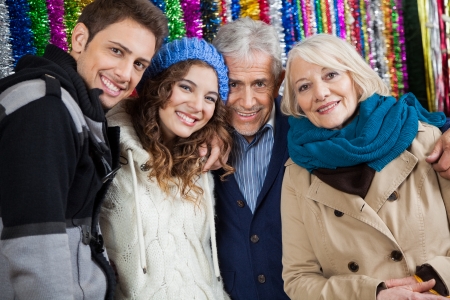 Portrait of happy family standing together against tinsels at storeの写真素材