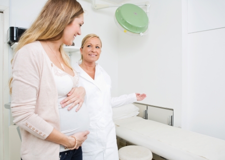 Female gynecologist gesturing while looking at pregnant woman in clinicの写真素材