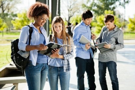 Happy young students reading books in university campusの写真素材