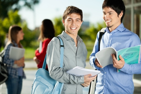 Portrait of happy young man with friend standing on college campusの写真素材