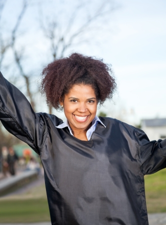 Portrait of happy young woman in graduation gown on college campusの写真素材