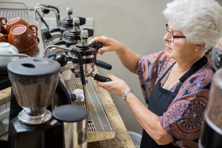 Senior female barista preparing coffee in cafeの写真素材