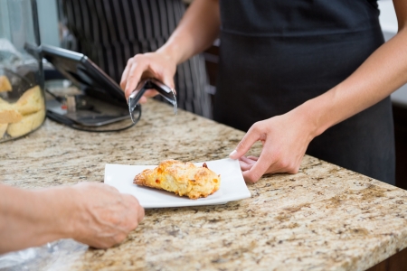 Midsection of waitress serving sweet food to woman at cafe counterの写真素材