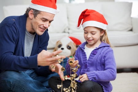 Smiling father and daughter looking at Christmas decorations at homeの写真素材