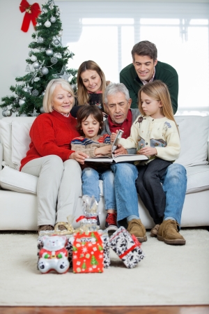 Three generation family looking at book in houseの写真素材