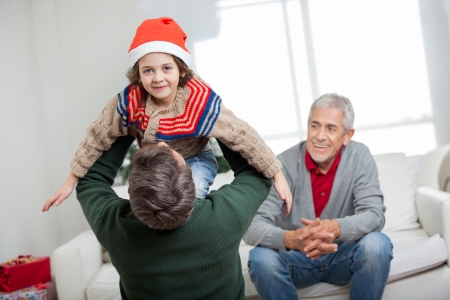 Portrait of boy being carried by father with grandfather looking at them during Christmas at homeの写真素材