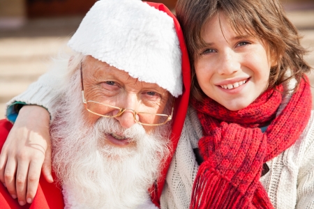 Closeup portrait of boy and Santa Claus smiling outdoorsの写真素材