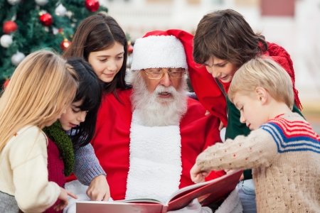 Children and Santa Claus reading book in courtyardの写真素材