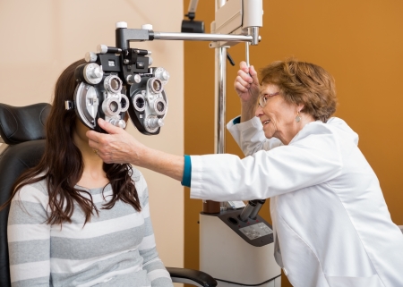 Senior female optometrist examining young woman's eyes in storeの写真素材