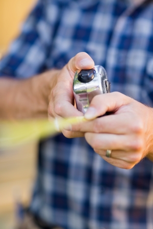 Midsection of carpenter holding tape measure