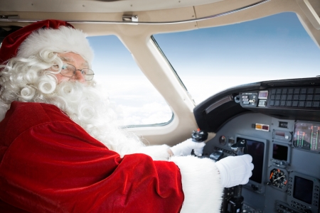 Portrait of man in Santa costume holding control wheel in cockpit of private jetの写真素材