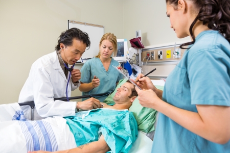 Doctor and nurses examining young patient in hospitalの写真素材