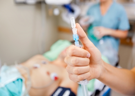 Cropped image of nurse holding syringe with patient and colleague in background at hospitalの写真素材