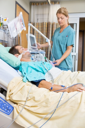 Nurse examining male patient lying on bed in hospitalの写真素材
