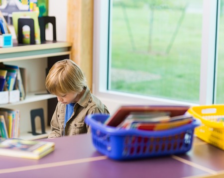 Schoolboy reading book in libraryの写真素材