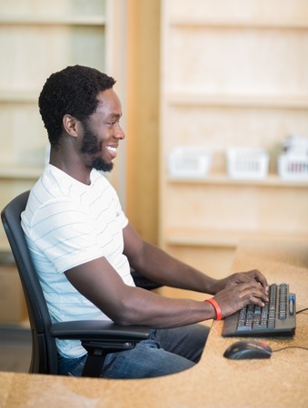 Side view of male librarian working on computer at library deskの写真素材
