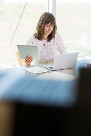 Female college student using technologies while studying in libraryの写真素材