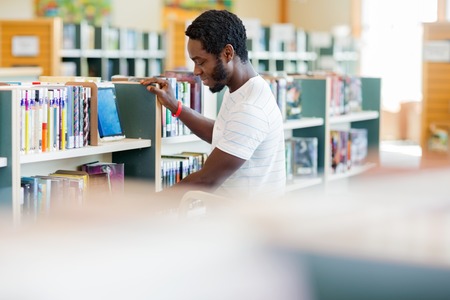 Side view of African American male librarian arranging books in bookstoreの写真素材